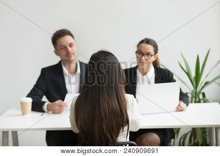Back Close Up View Of Female Applicant Being Interviewed By Two Hr Managers Reading Her Resume, Chec