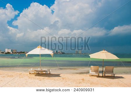 Sun Loungers And A White Umbrellas For Tourists On The Beach In Cancun. Mexico.