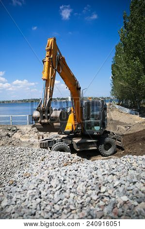 Big Excavator On New Construction Site. Excavator Loader Machine During Earthmoving Works Outdoors A