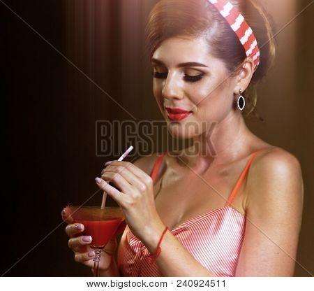 Pin up girl drink bloody Mary cocktail and dreams. Pin-up retro female style. Saturated, bright color combinations on retro party. Sun flare of dances at theme