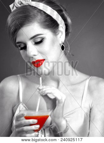 Pin up girl drink bloody Mary cocktail. Pin-up retro female style. Girl wearing light dress seduces men. Retro image of girl thoughtful and multifaceted. Black and white retro portrait with red accent