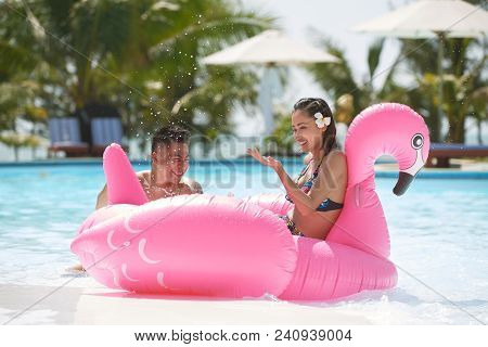 Joyful Young Vietnamese Couple Having Fun With Inflatable Pink Flamongo