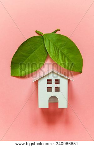 Miniature Toy Model House With Green Leaves On Pink Pastel Colourful Trendy Backgdrop. Eco Village, 