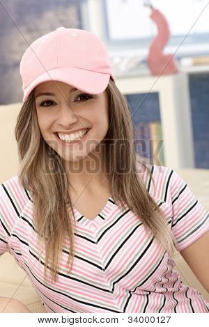 Sportieve meisje glimlachend in roze Baseballcap thuis.