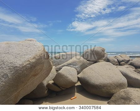 Large Rocks On The Beach By The Sea And There Are Plastic Bottles Of Orange Shampoo That Are Rubbish