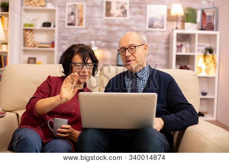 Elderly Old Couple Using Modern Laptop To Chat With Their Grandson