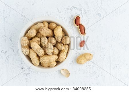 Top View Plate With Peanut In Endocarp, Bowl With Drupe In Shell On A White Table. Stone Background,