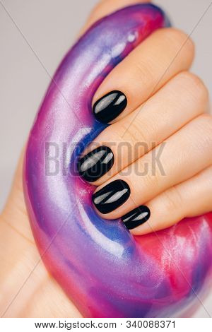 Hands With Black Manicure Holding Slime In Blue And Pink Vibrant Colors