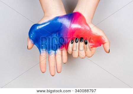 Hands With Black Manicure Holding Slime In Blue And Pink Vibrant Colors