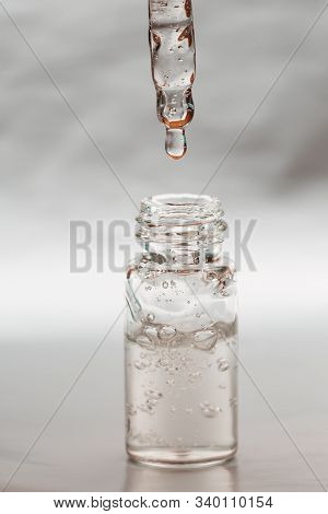 Bottle Of Hyaluronic Acid With Pipette On Silver Background. Front View.