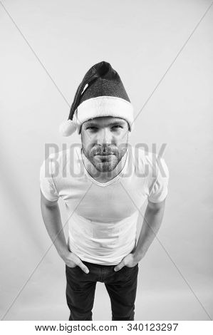 Man Look With Squinty Eyes In Red Santa Hat And White Tshirt On Orange Background. Santa Claus Fashi