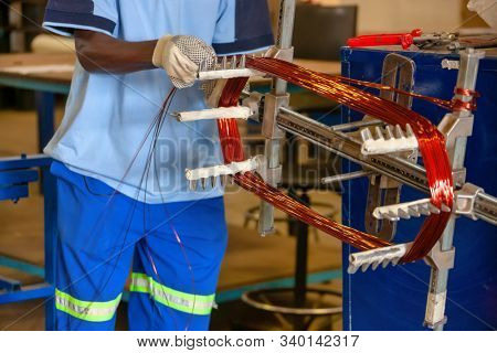 African man winding copper on the  grill to size,  rewinding an electric motor