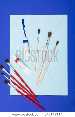 Drawing Set Sach As Brushes, Note, Scetchbook, Paints, Oil And Cup Of Coffee Isolated On Blue Backgr