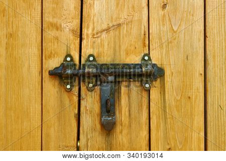 Iron latch and yellow wooden gate closeup on the ranch house for background or texture
