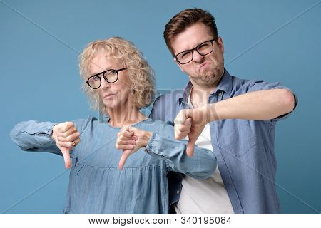 Two Dissappointed Senior And Young Citizens Holding Their Thumbs Down