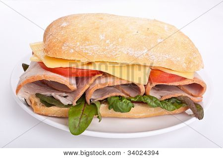 Ciabatta-Brot-Sandwich, gefüllt mit Fleisch, Käse und Gemüse auf einem Teller