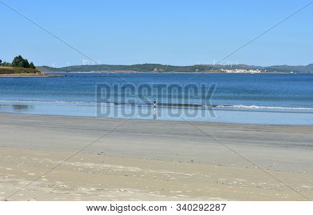 Beach With Wet Sand, Woman And Blue Sky. Muxia, Spain.
