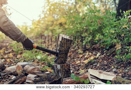 Man Cuts A Log With An Industrial Ax. Parts Of The Tree Fly Apart. A Strong Man Holds An Ax In His H