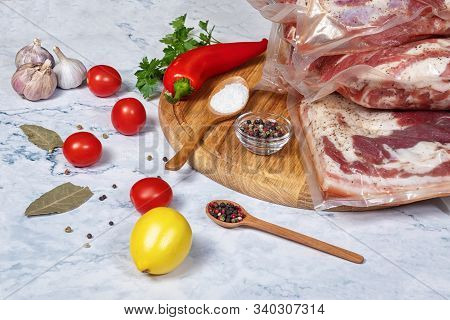 Concept Of The Sous Vide Cooking. The Meat Is Vacuum Packed Spices And Salt On A Light Background.