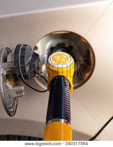 Fuel Pump Inserted In The Gas Tank Hatch. Refueling A Passenger Car With Gasoline. Yellow Fuel Pump 