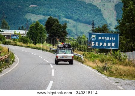 Berane, Montenegro - July 21, 2014. Vintage Off Road Car Passing By Signboard In Native Serbian Lang
