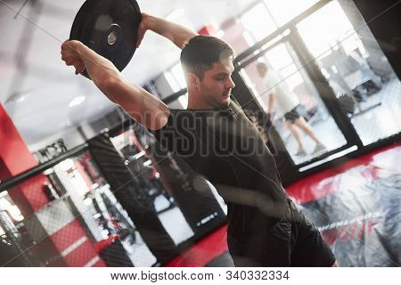 Man Has Workout In The Gym. Having Exercise With Pancakes For The Rod.