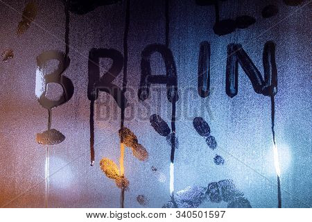 The Word Brain Written On Night Wet Window Glass With Palm Prints Close-up With Blurred Background