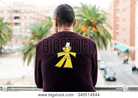 young man outdoors with a paper man in his back as a prank for the dia de los inocentes, the innocents day, a feast held in spain, hispanic america and philippines equivalent to april fools day