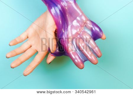 Hands With Holding Slime In Purple Color On Blue Background