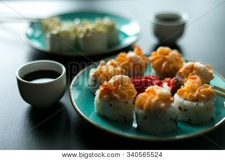 Cream Rolls With Soy Sauce Ginger And Wasabi On A Black Table And Blue Plates With Chopsticks