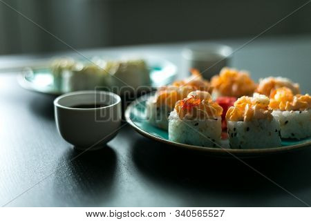 Cream Rolls With Soy Sauce Ginger And Wasabi On A Black Table And Blue Plates With Chopsticks