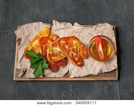 Sliced ​​halumi Cheese With Spices. On A Wooden Board. Decorated With Spices And Parsley. Next To Th