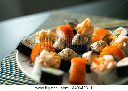 Set Of California Rolls, Butter Cream, Shrimp On A White Platter And A Black Table. With Ginger Soy 