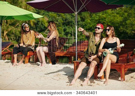 Young People Playing Ukulele, Having Cold Drinks And Discussing Beautiful Seascape When Resting On C