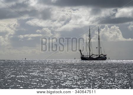 Sailboat Against The Glare Of The Sun In The Wadden Sea Near The Island Of Terschelling