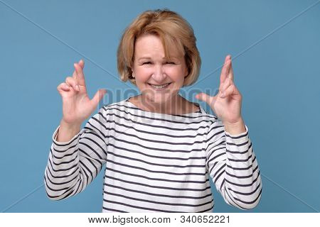 Senior Woman Crossing Fingers For Good Luck, Hoping Her Wishes Will Come True