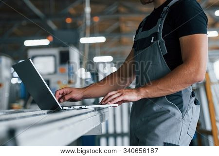Modern Laptop. Typing On Keyboard. Industrial Worker Indoors In Factory. Young Technician With Orang
