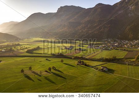 Aerial View Of Green Meadows With Villages And Forest In Austrian Alps Mountains.