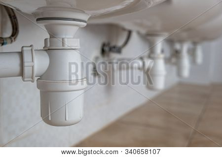 Close Up Of White Plastic Pipe Drain Under Washing Sink In Bathroom.