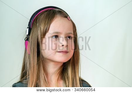 Pretty Smiling Cild Girl Listening To Music In Big Pink Earphones.