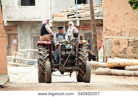 Tokat Turkey 05/17/2013 A Farmer Driving His Tractor In The Middle Of A Village. Two Women Riding Wi