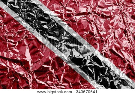 Trinidad And Tobago Flag Depicted In Paint Colors On Shiny Crumpled Aluminium Foil Closeup. Textured