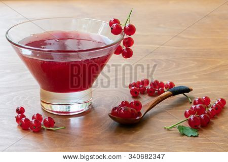Glass Bowl Of Red Current Jam With Wooden Spoon Full Of Many Ripe Juicy Red Current Berries On Dark 