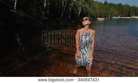 Woman Walk On Water On Pier In Sunglasses And A Boho Silk Shawl. Girl Rest On Flood Wood Underwater 