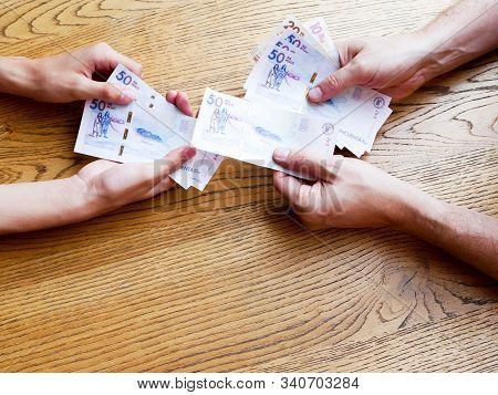 Hands Of A Man Giving Fifthy Thousand Pesos Bills To A Young Over A Table