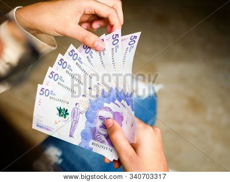 Closeup Of A Woman Counting Fifthy Thousand Pesos Bills Forming A Range On One Of Her Hands