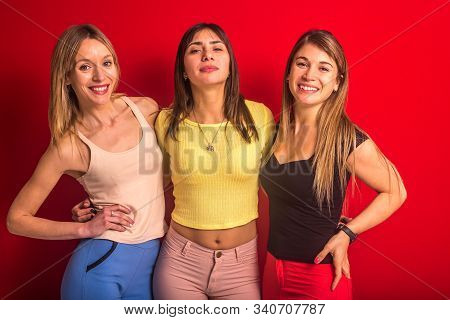 Stock Studio Photo Of Three Girls Posing Standing In Front Of A Red Wall