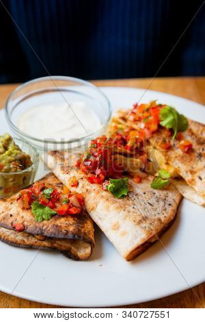 Delicious Mexican quesallidas made with chicken, tomato pieces and served with guacamole sauce.