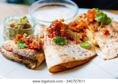 Delicious Mexican quesallidas made with chicken, tomato pieces and served with guacamole sauce.