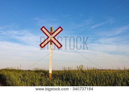 Lone Railroad Crossing Sign On Green Prairie Under Blue Summer Sky